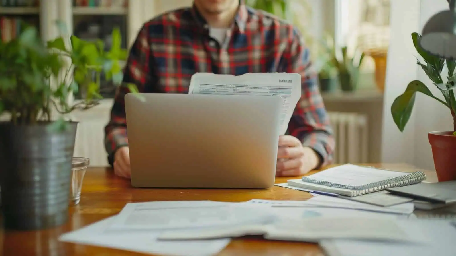 Belege und Laptop auf einem Schreibtisch: Wer aus Shopify Rechnungen versenden will, bewahrt sie acht Jahre auf